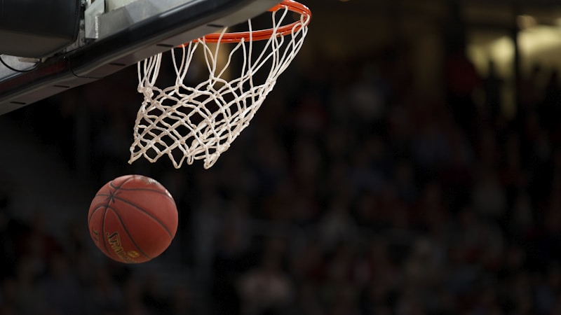 NBA篮球比赛精彩瞬间，洛杉矶湖人队球员突破上篮，球馆内紫色与金色灯光闪耀